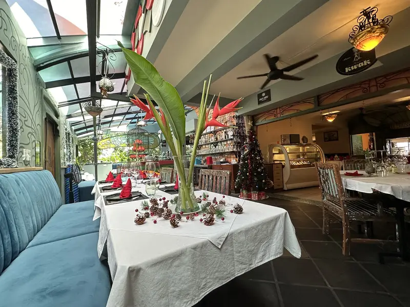 Glass-roofed dining room with blue banquettes and white tablecloths