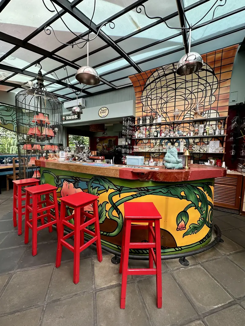 The painted bar with red stools under the glass roof
